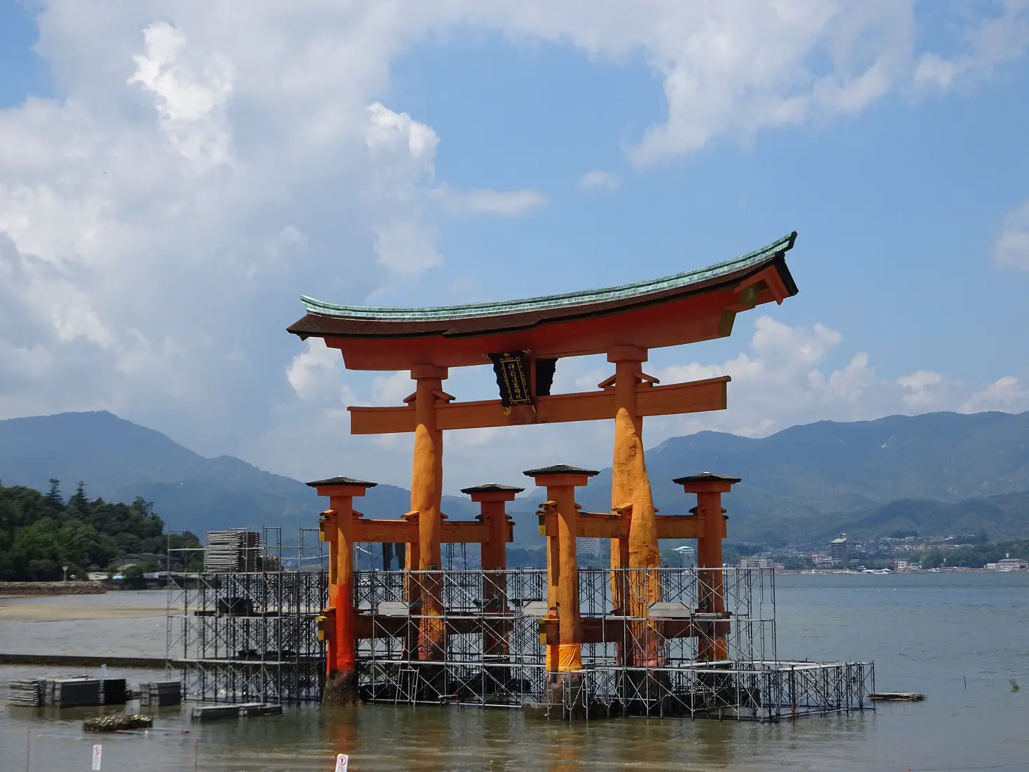 The red wooden torii of Itsukushima Shrine standing in the water in front of Miyajima Island, Japan