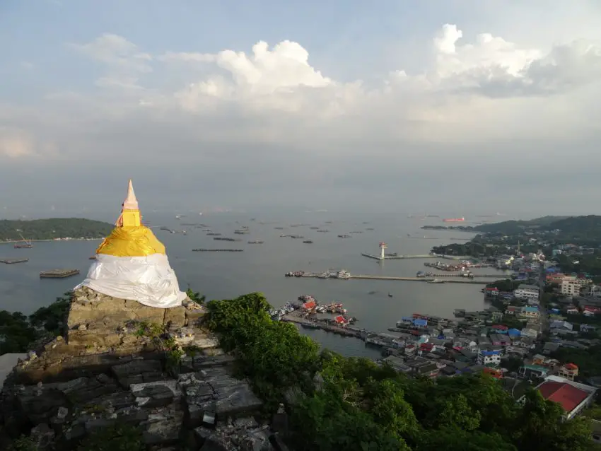 A white stupa cloaked with golden cloth on a hill above a bay