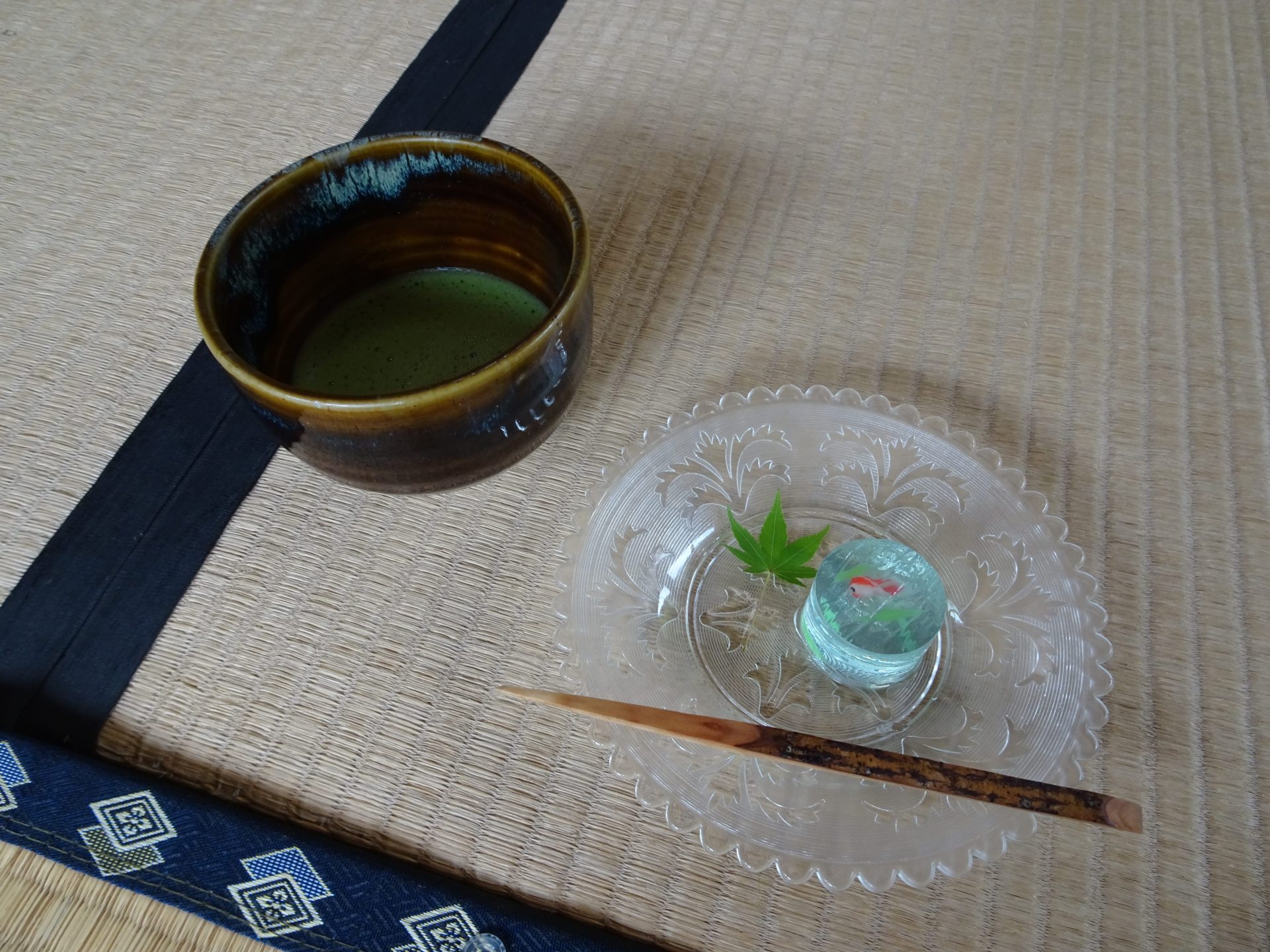 A cup of matcha tea and a Japanese sweet on a tatami mat