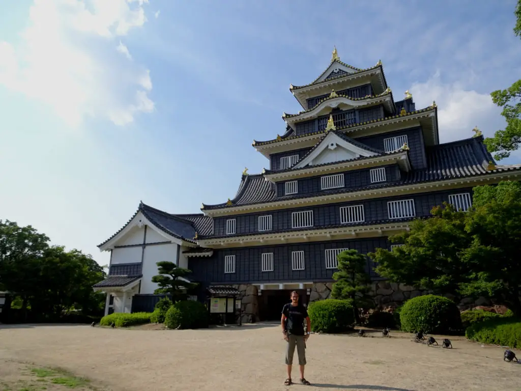 A man standing in front of a black Japanese castle