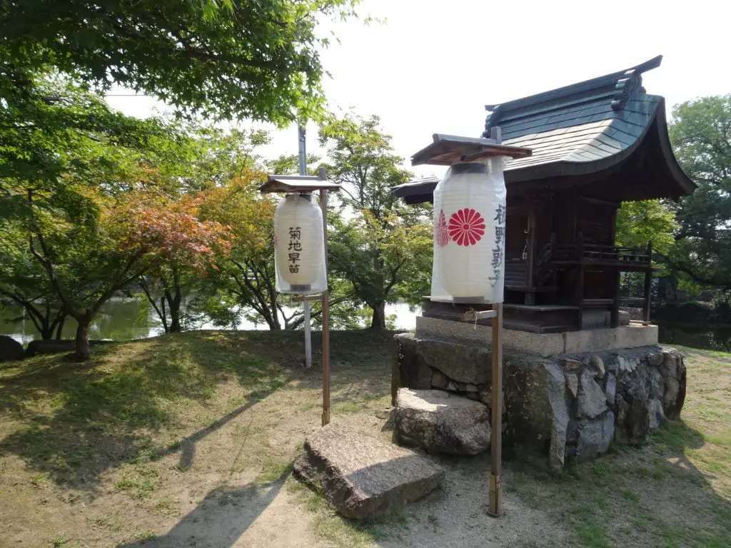 A small wooden shrine on an islet wit paper lanterns in front