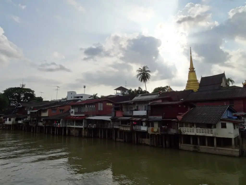 Wooden houses along a waterfront with a golden chedi in the background
