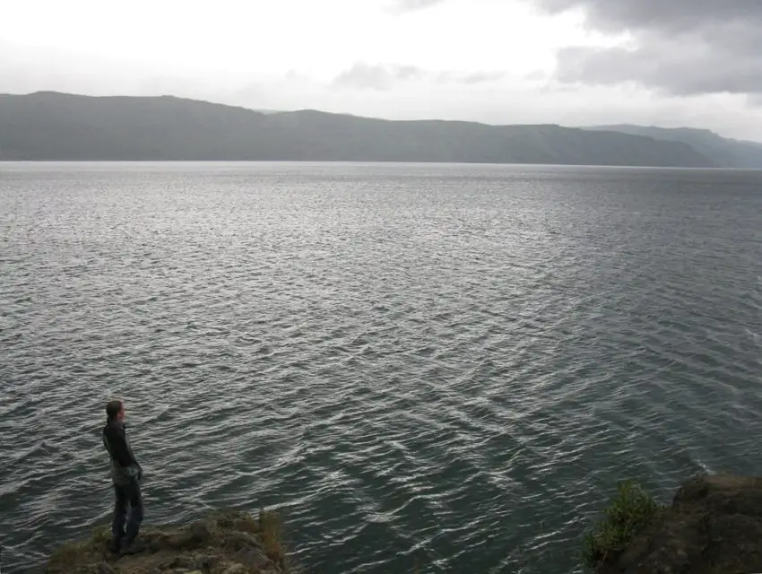 A man standing on a rock near a giant lake