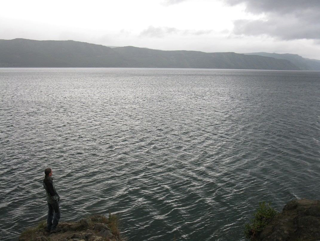 A man standing on a rock near a giant lake
