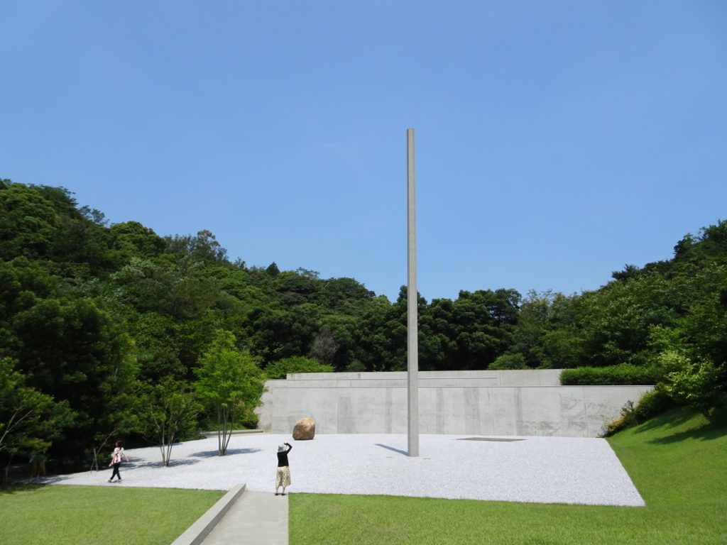 A bunker-like concrete structure with a tall spire in front