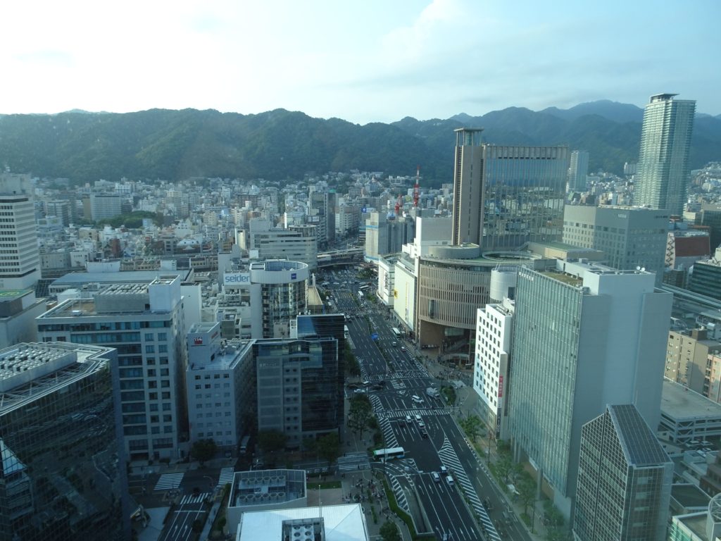 A birds eye view of a modern city of skyscrapers with mountains in the background