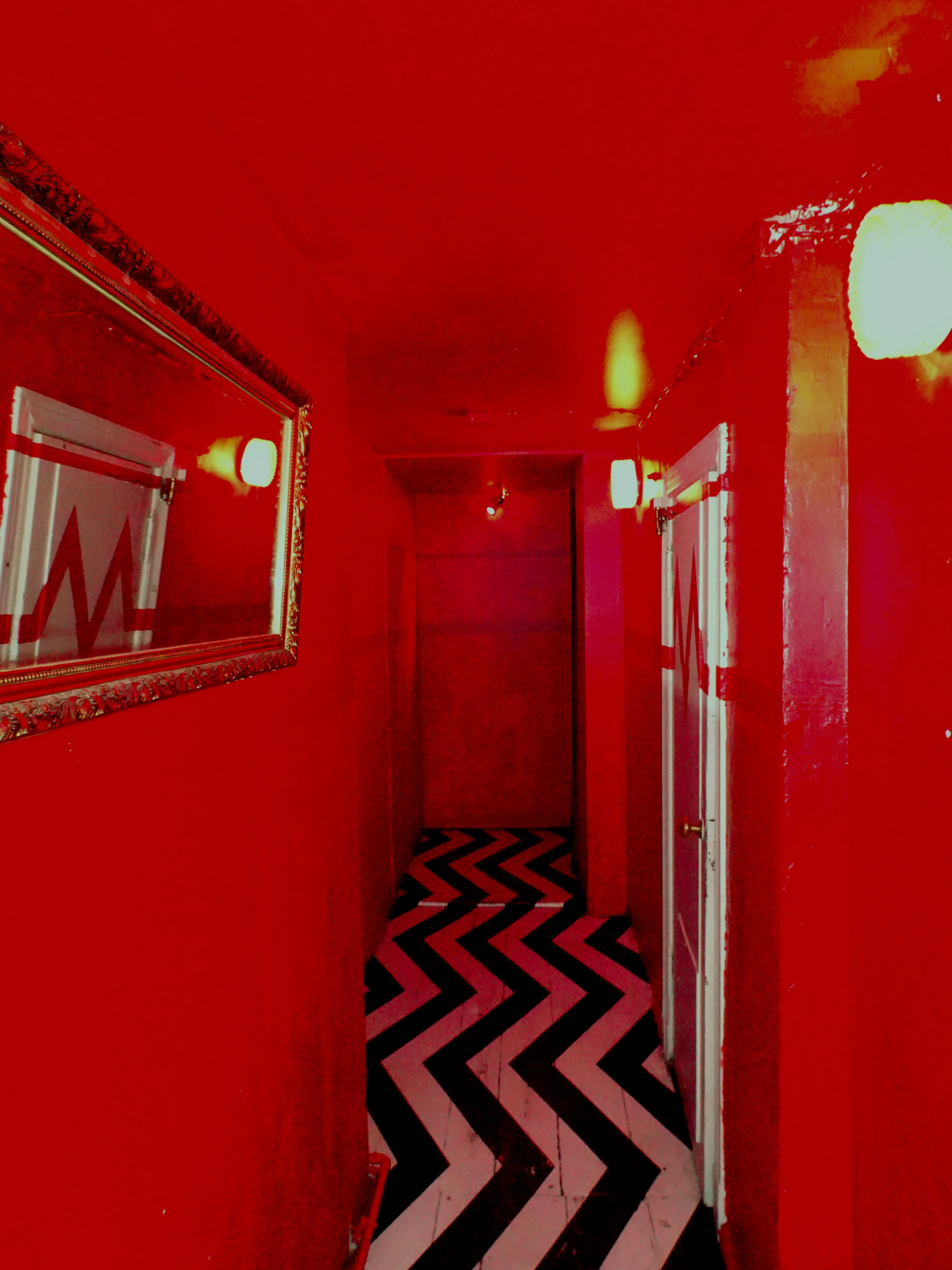 A red-walled corridor with a white-and-black zig-zagging pattern on the floor