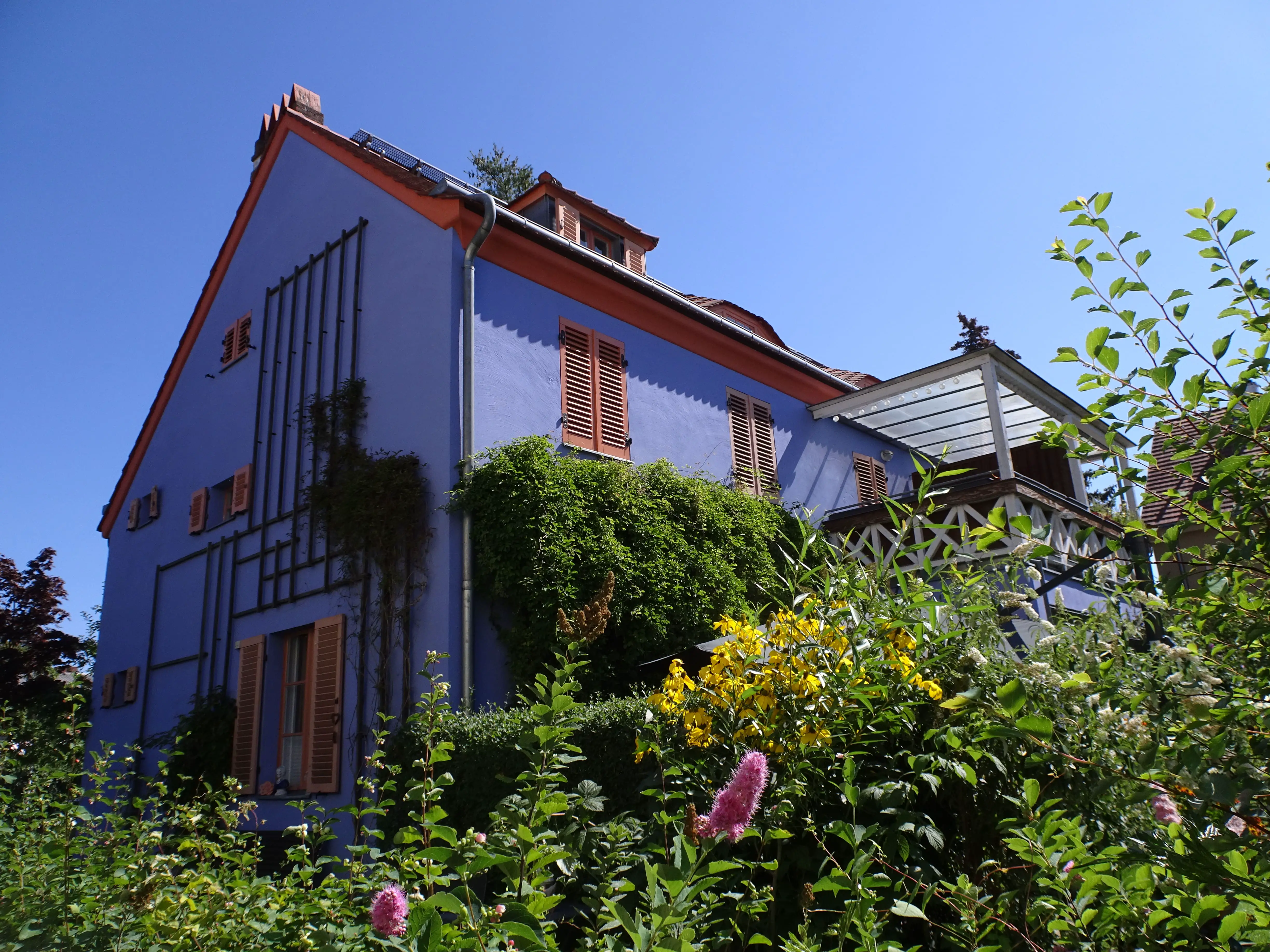 A blue-painted house with a flowery garden