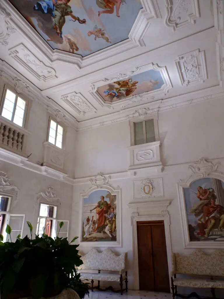 A white-painted room with painted images of allegorical figures