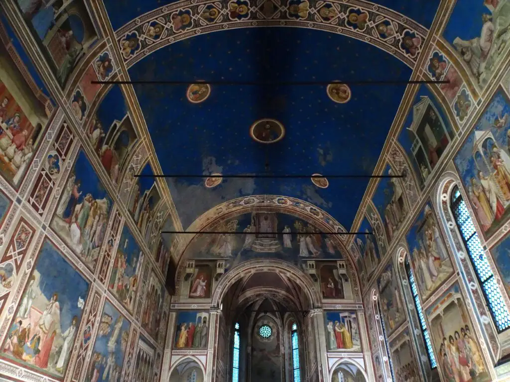 A chapel covered in countless frescoes with a blue-painted ceiling