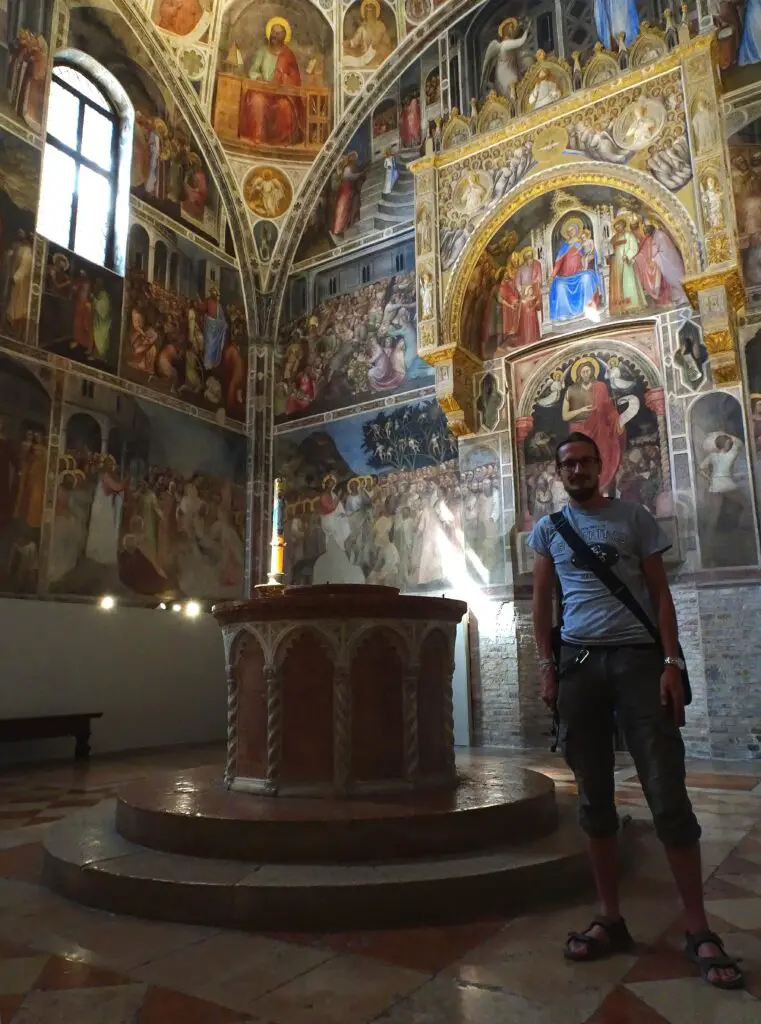 A man standing in a small room full of countless frescoes of Christ, saints and angels