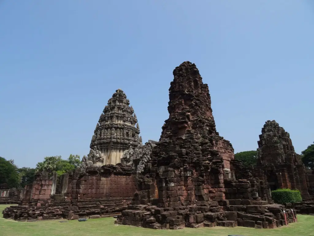 Three partially toppled brick towers of a Khmer temple