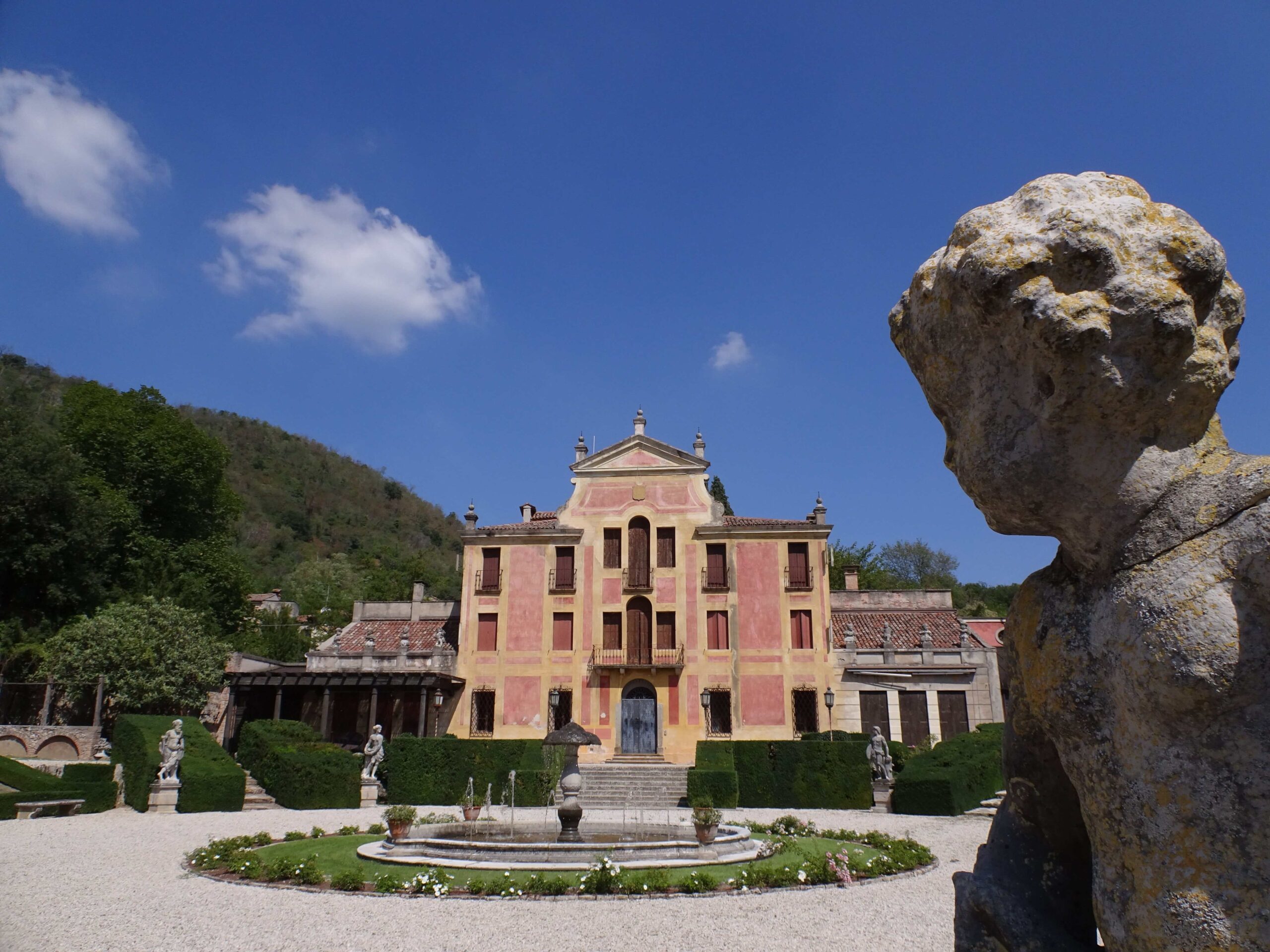 A red villa surrounded by fountains and statues