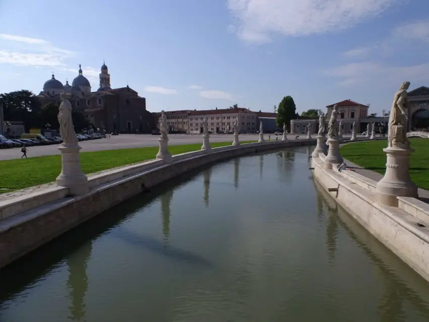 A canal surrounded by lawns and statues