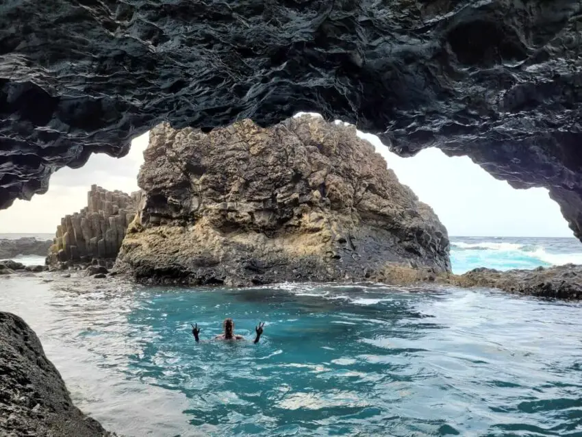 A man swimming in a natural pool in an open cave