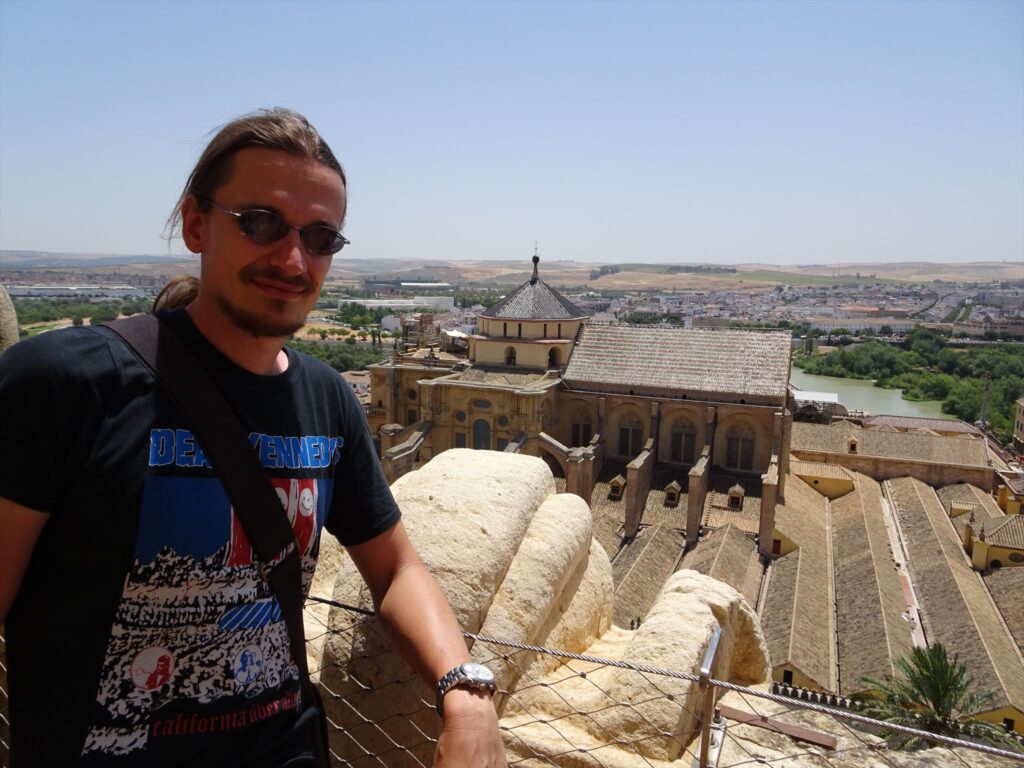 A man standing on a tower with a big mosque in the background