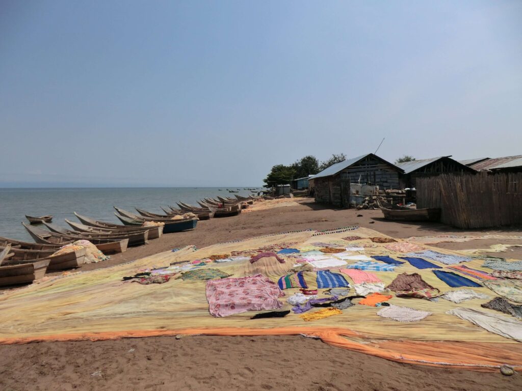 Colourful sheets drying near a lakeshore full of wooden boats