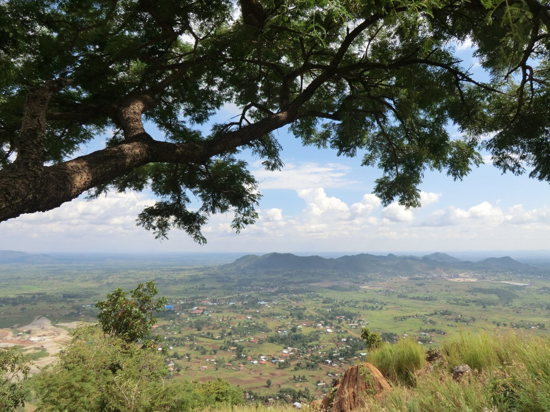 A green plain with some hills in the background seen from above