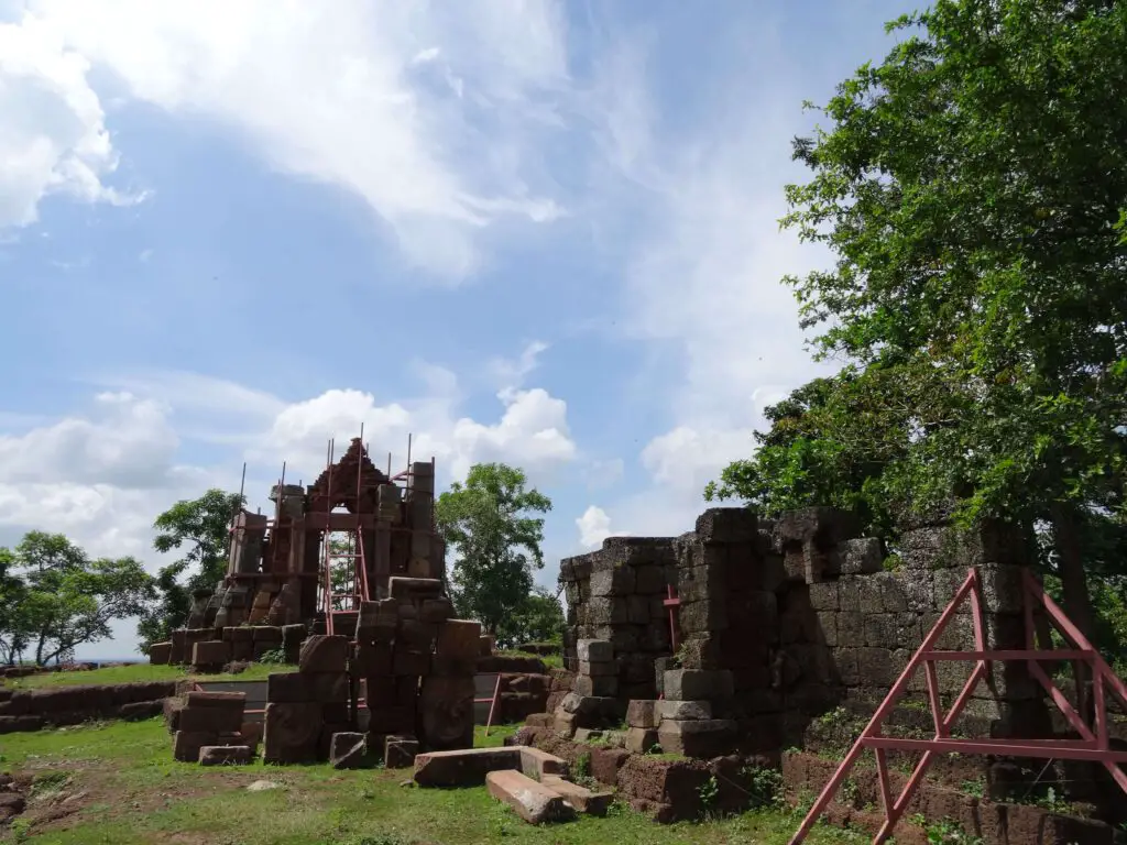 A small Khmer ruin surrounded by trees on a hilltop