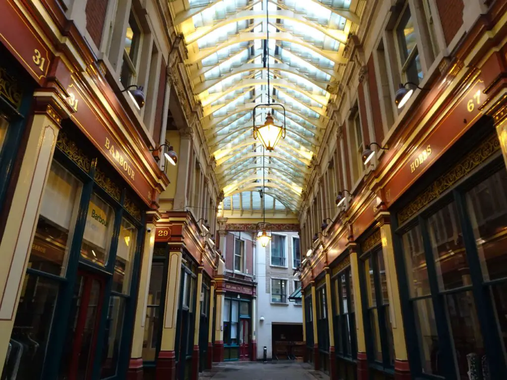 A covered Victorian arcade with an arced rooflight and lamps hanging from the ceiling