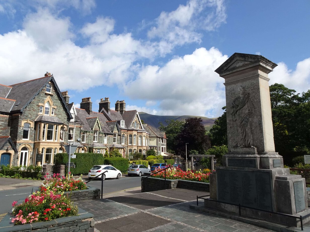A stone monument surrounded by flowers with stone houses in the background