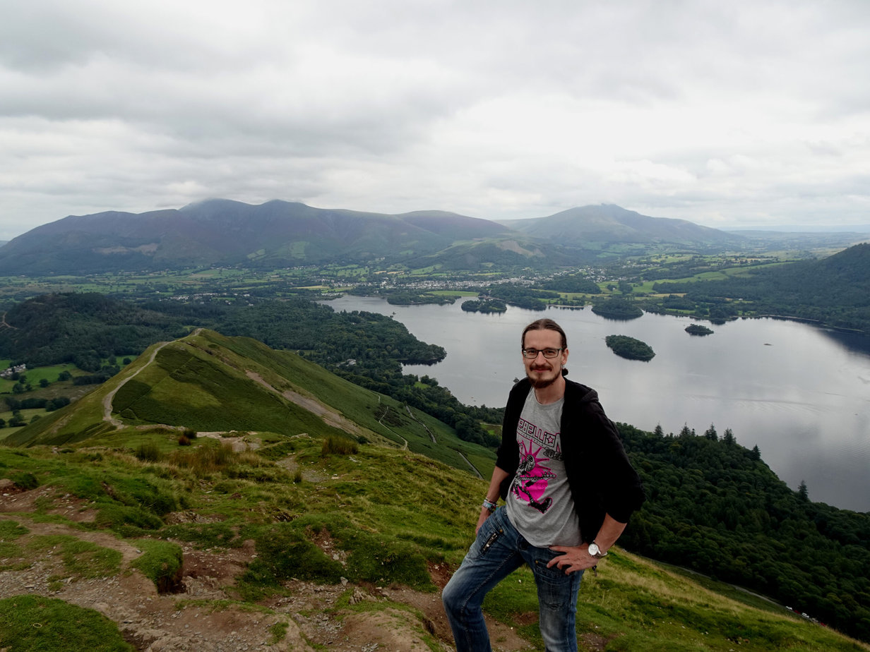 A man standing on a mountaintop with a lake in the background