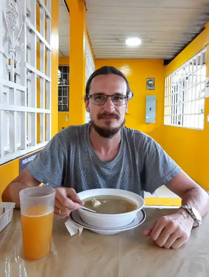 A man sitting in a restaurant eating a soup