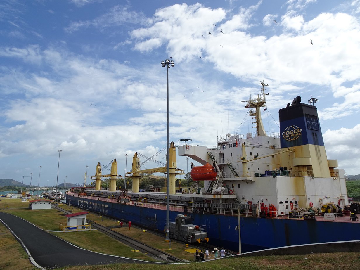 A huge container ship sitting high in a narrow canal
