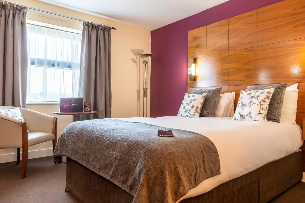 ein Hotelzimmer mit einem großen Bett und einem Stuhl in der Unterkunft Legacy Preston International Hotel in Preston