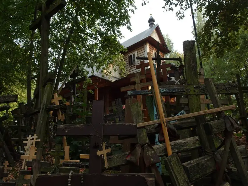 A wooden church on a hill surrounded by hundreds of wooden crosses