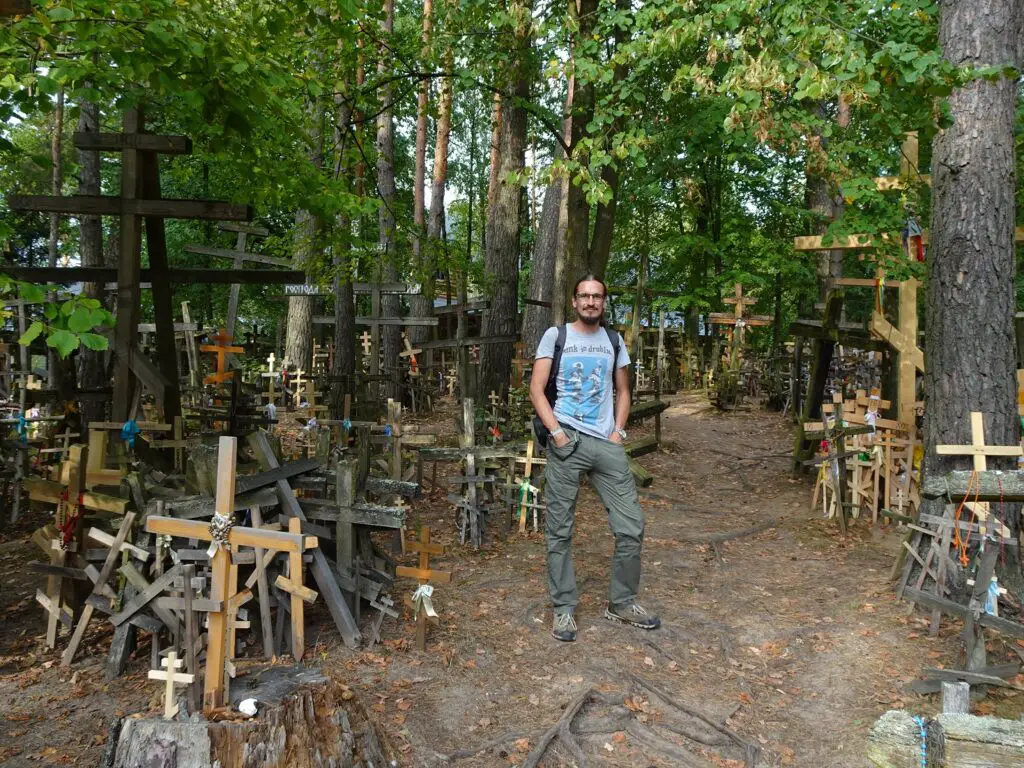 A man standing on a hill surrounded by hundreds of wooden crosses