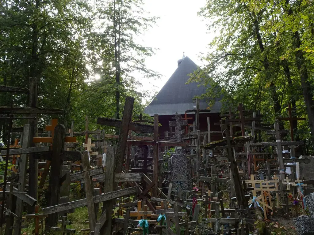 A wooden church on a hill surrounded by hundreds of wooden crosses