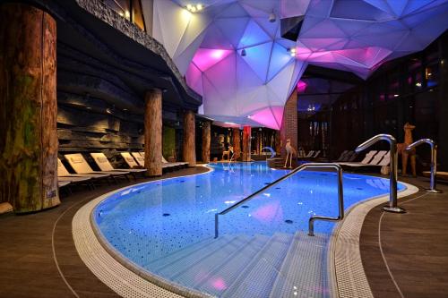 ein großer Pool in einem Gebäude mit lila Lichtern in der Unterkunft Hotel Żubrówka Spa & Wellness in Białowieża