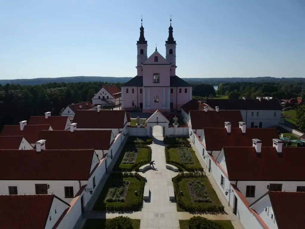 A grand monastery with gardens and monk's quarters in the foreground, seen from above