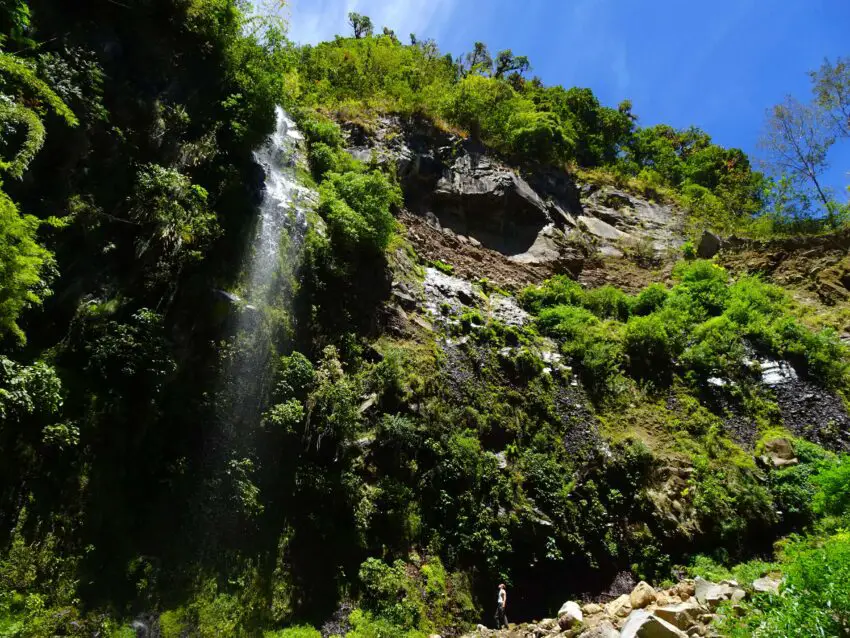 A man looking at a tall waterfall running over a cliff