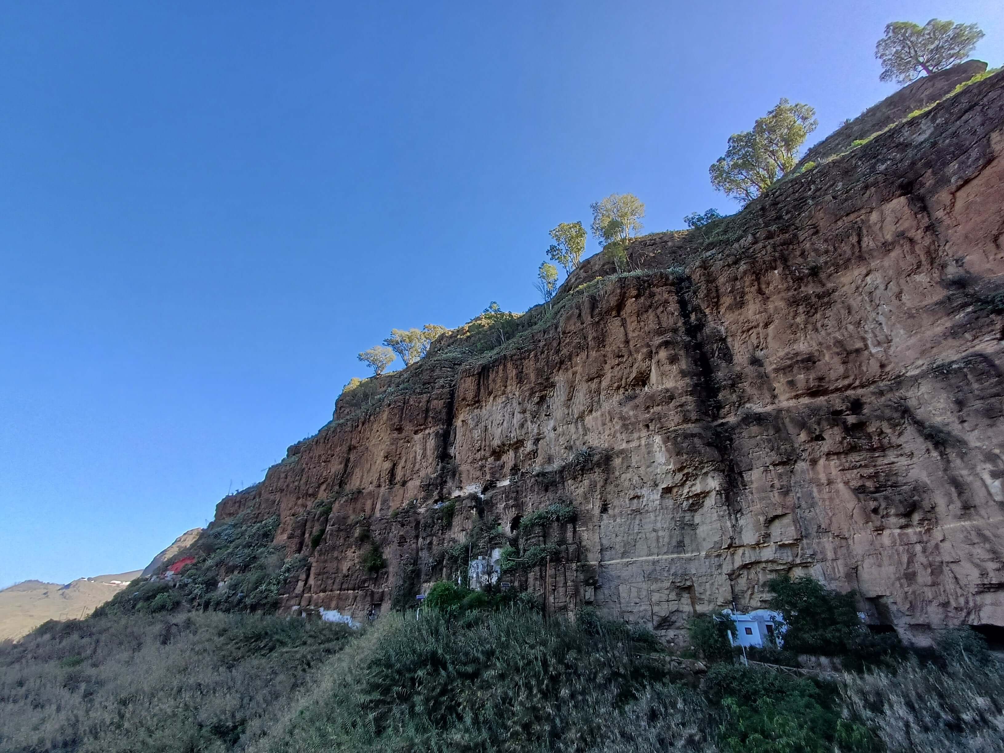 A tall cliff with artifical cave-homes cut in the side of it