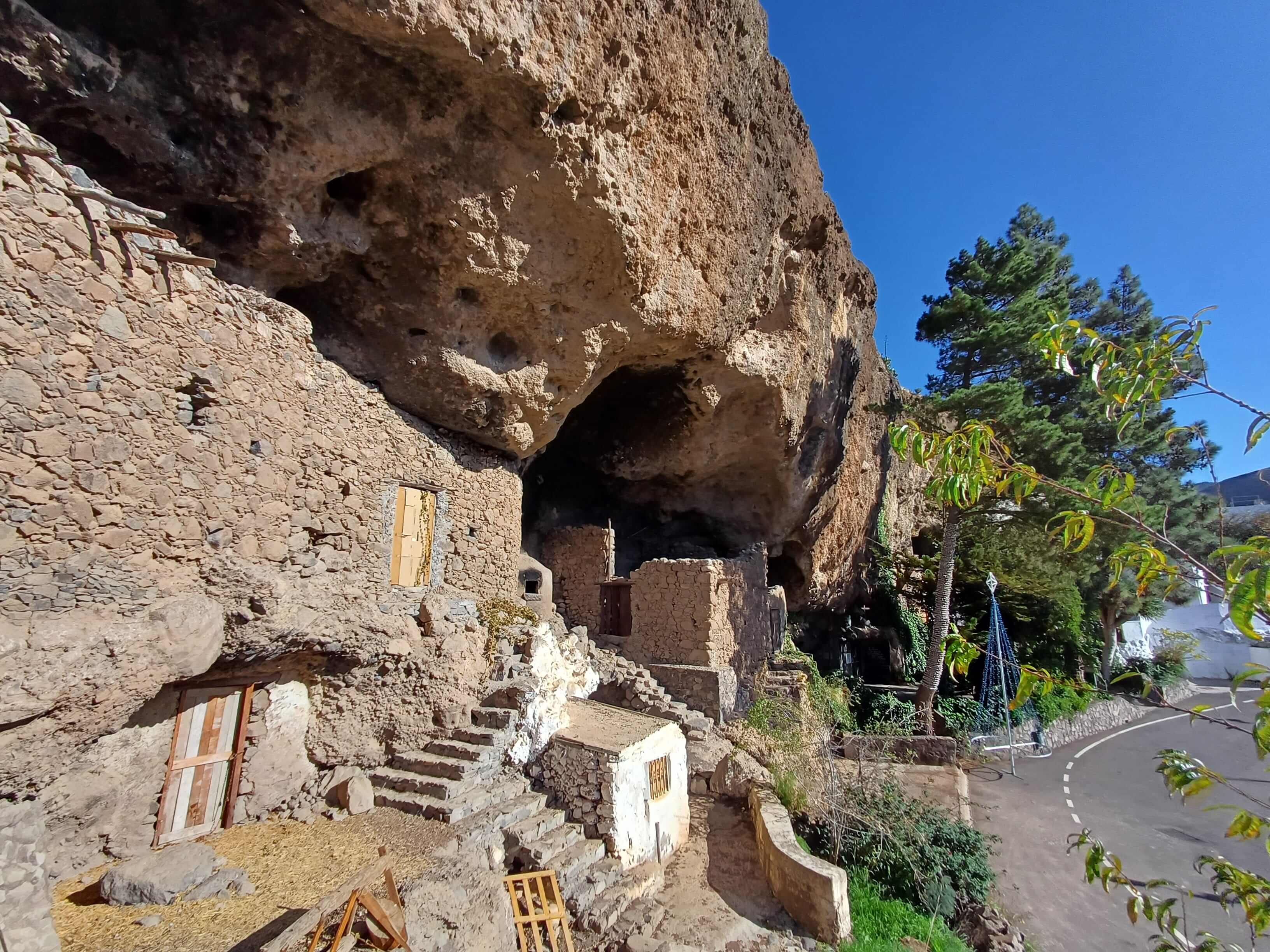 a cliff with artificial cave-homes cut in the side of it and a street on one side