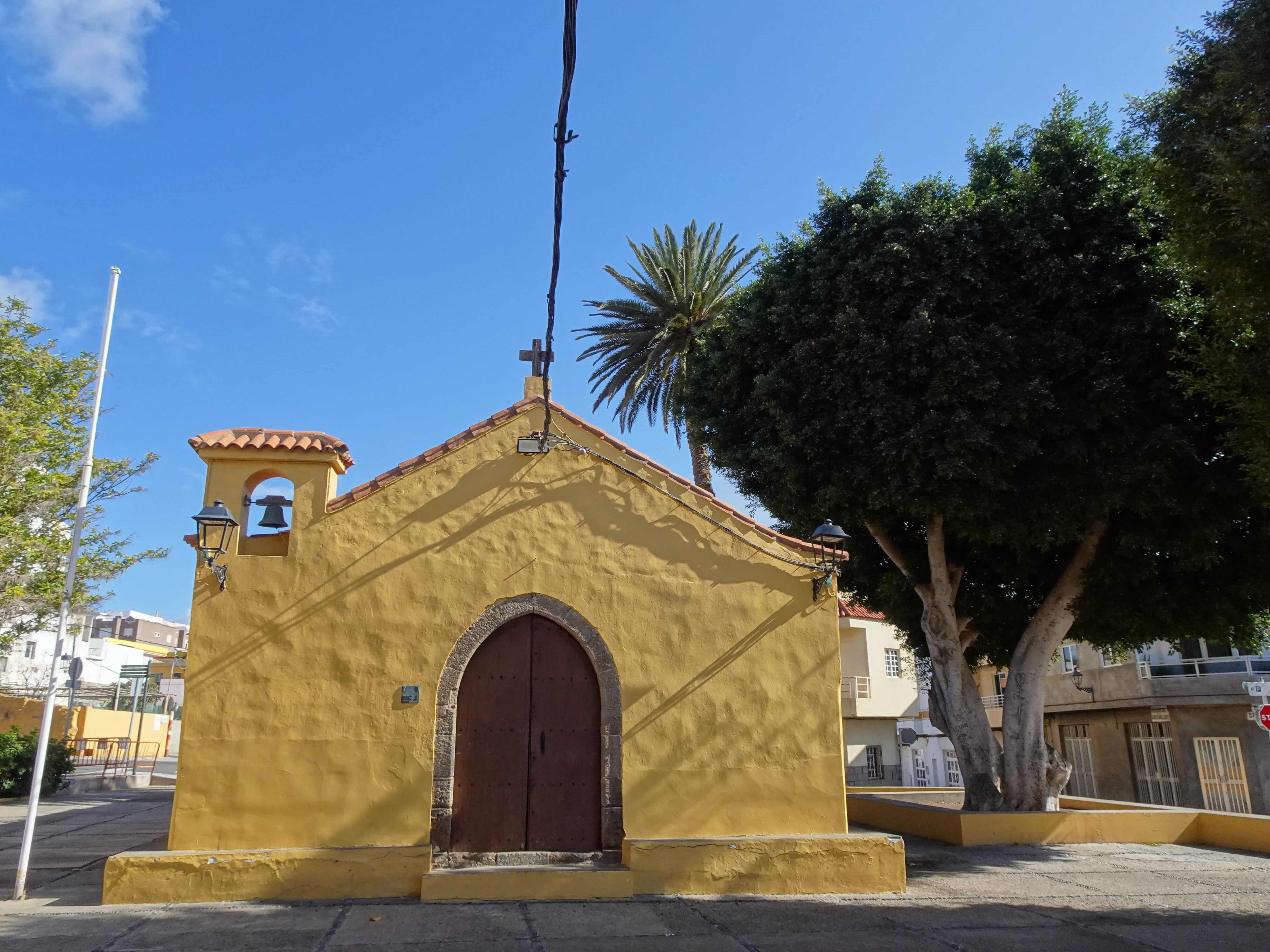 A small yellow chapel surrounded by trees