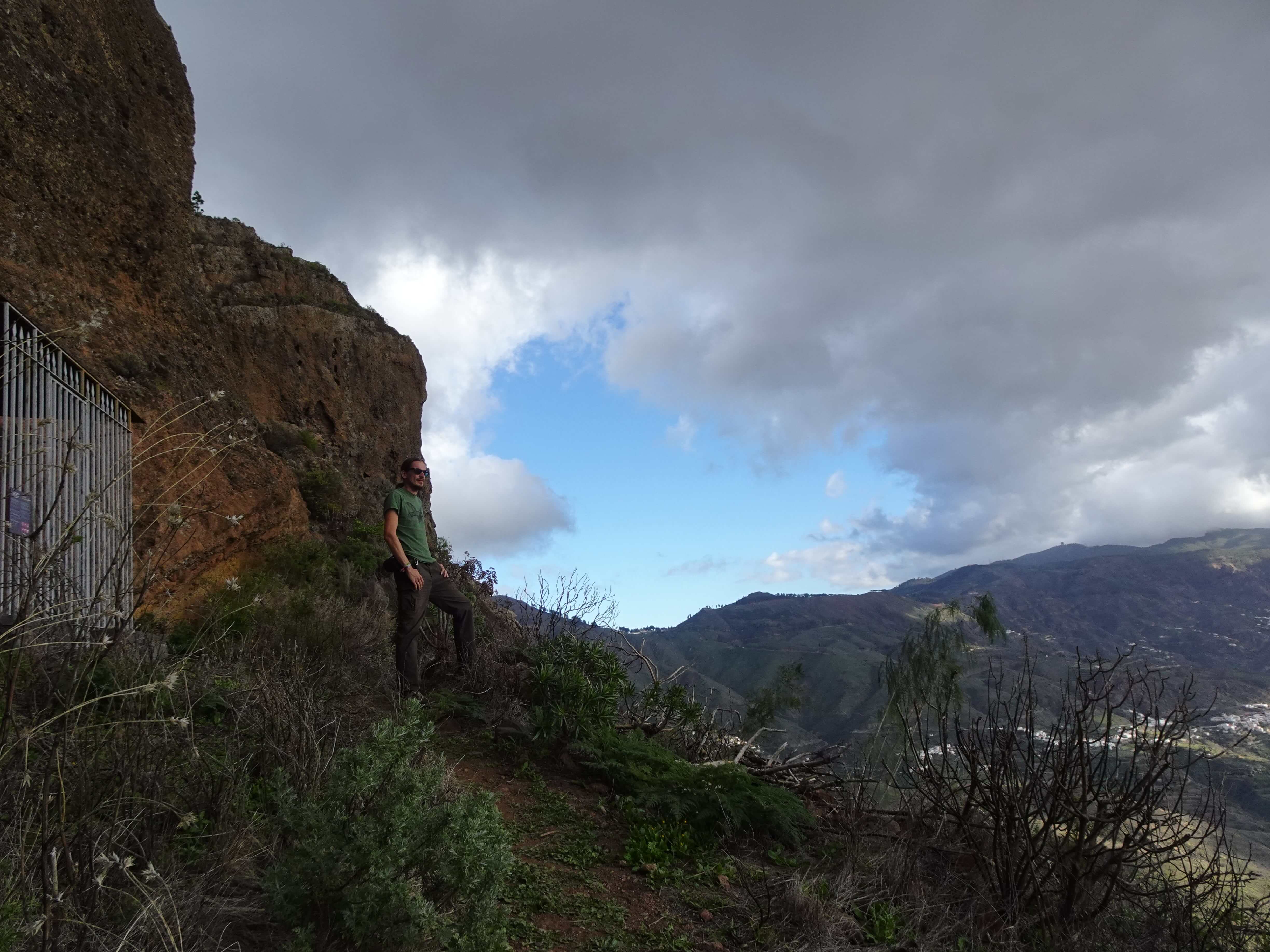 A cave in a cliff with a series of mountains in the background