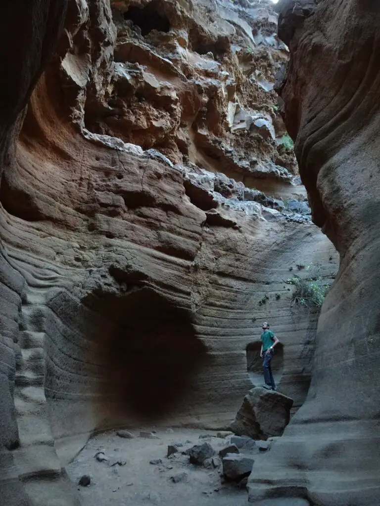 A man standing on a rock in a narrow slot canyon