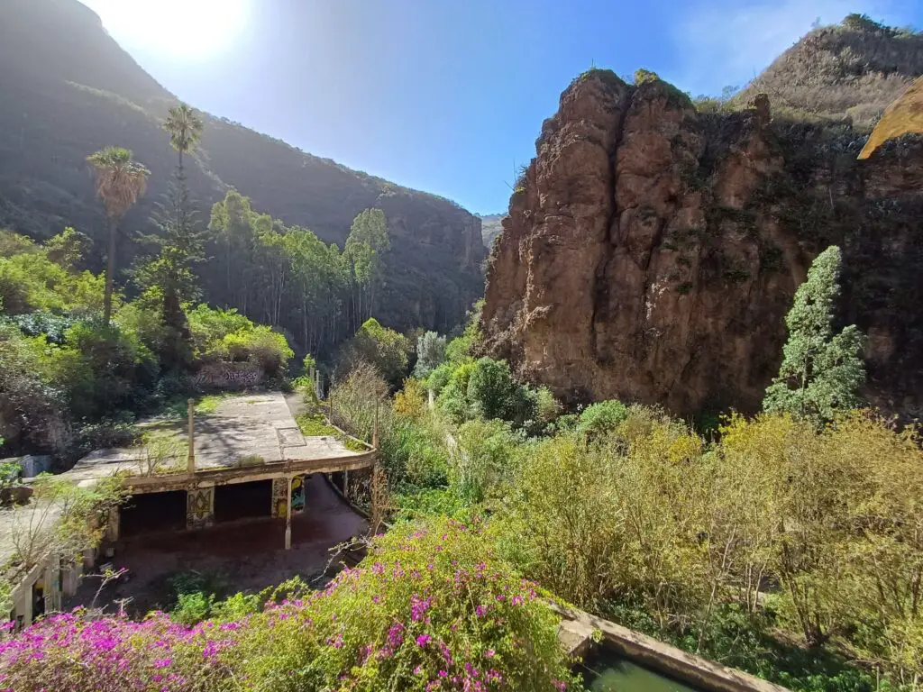 An old abandoned hotel ruin in a narrow ravine, surrounded by vegetation