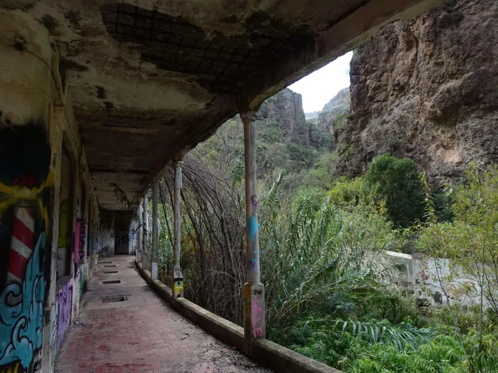 A collonaded walkway surrounded by lush vegetation