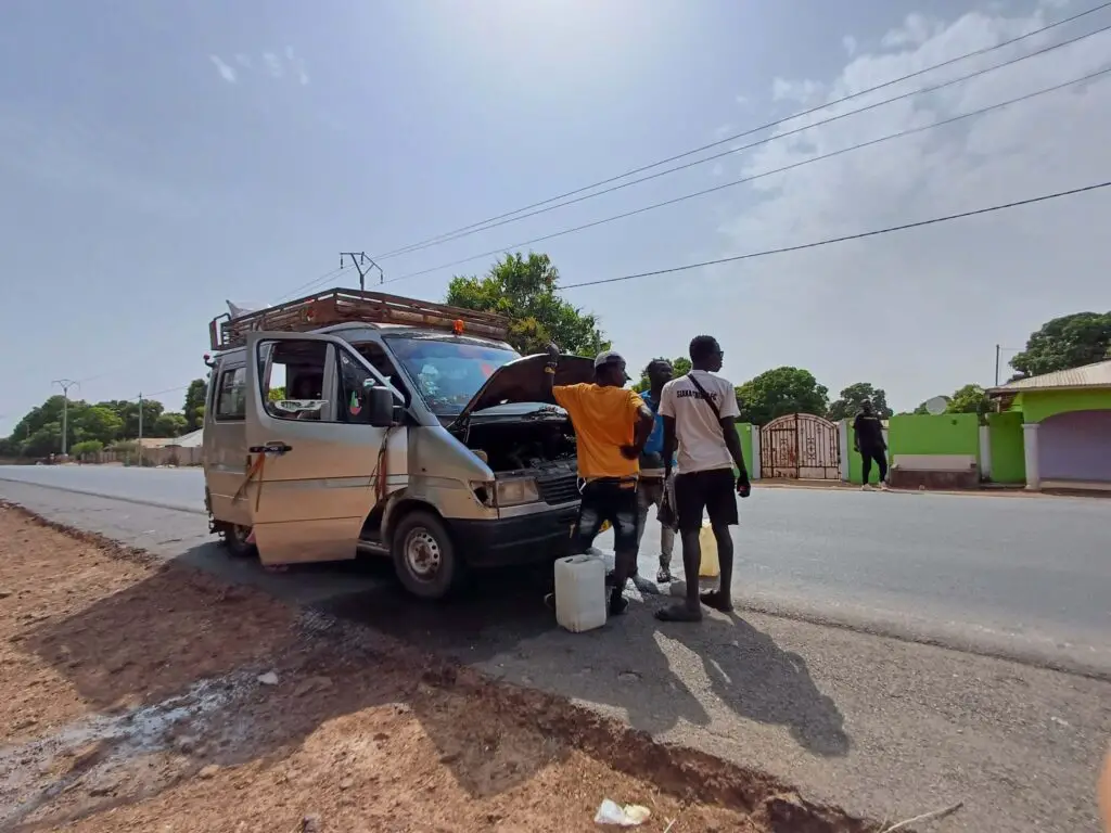 A group of men looking into the engine of a big minibus by the roadside