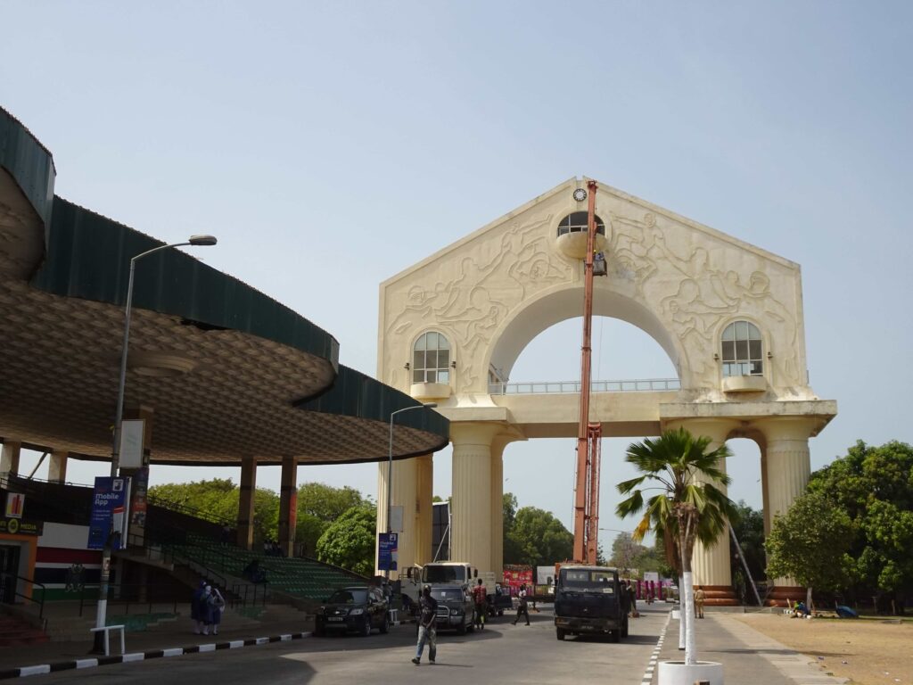 A tall beige archway at the end of an avenue