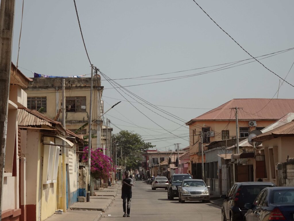 A man walking along a street between low houses