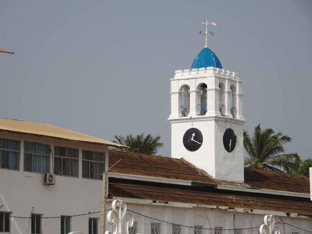 A blue-and-white painted clock tower atop a broad building
