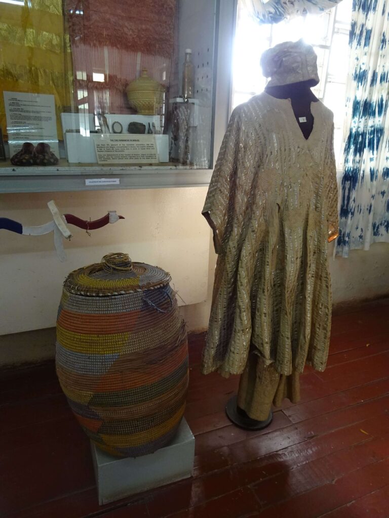 A museum display of a basket and a traditional dress