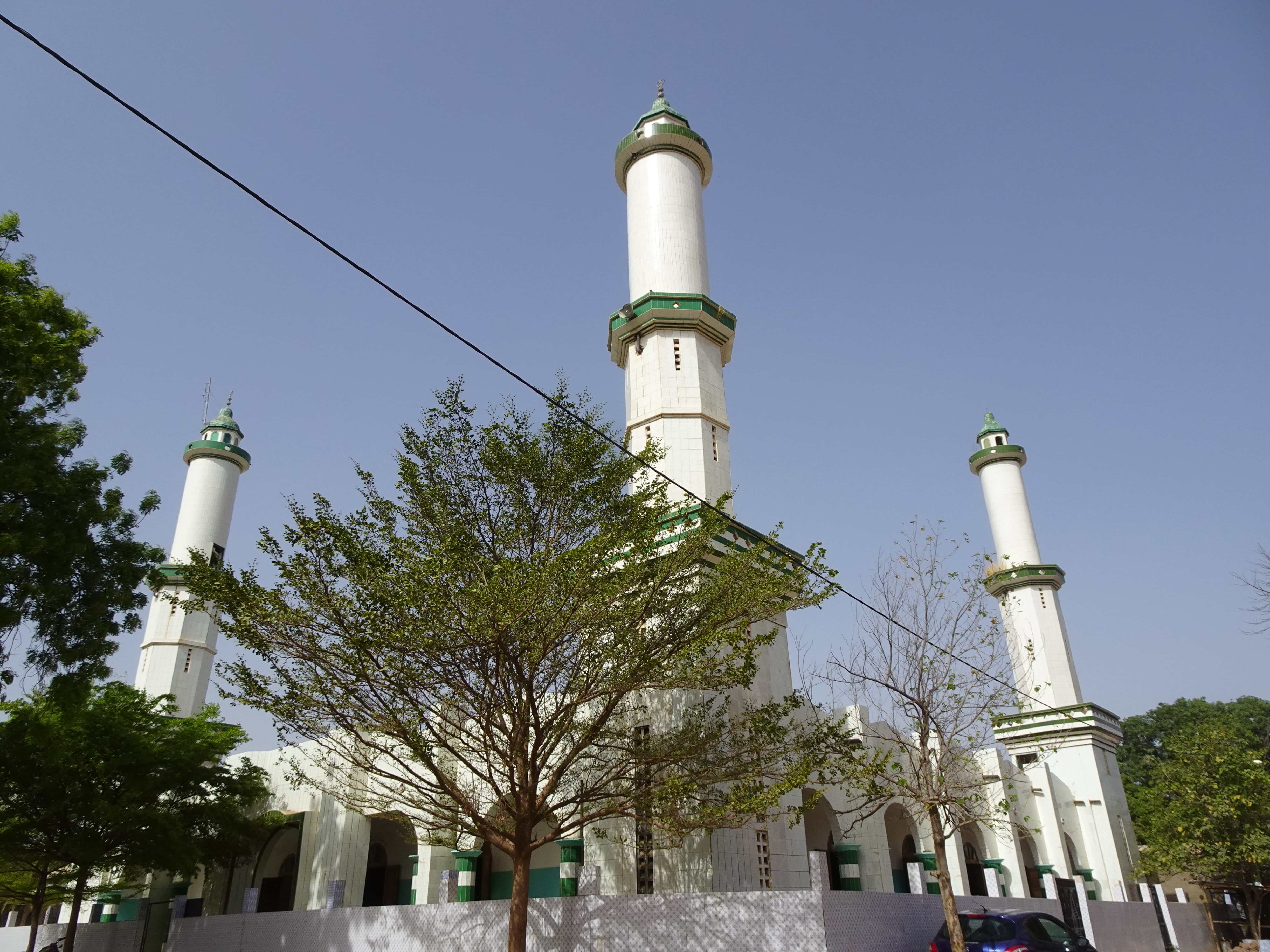 A big mosque with tall white minarets surrounded by trees