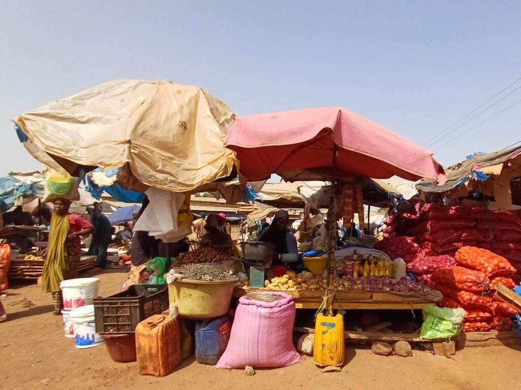 A market stall selling vegetables under two big umbrellas
