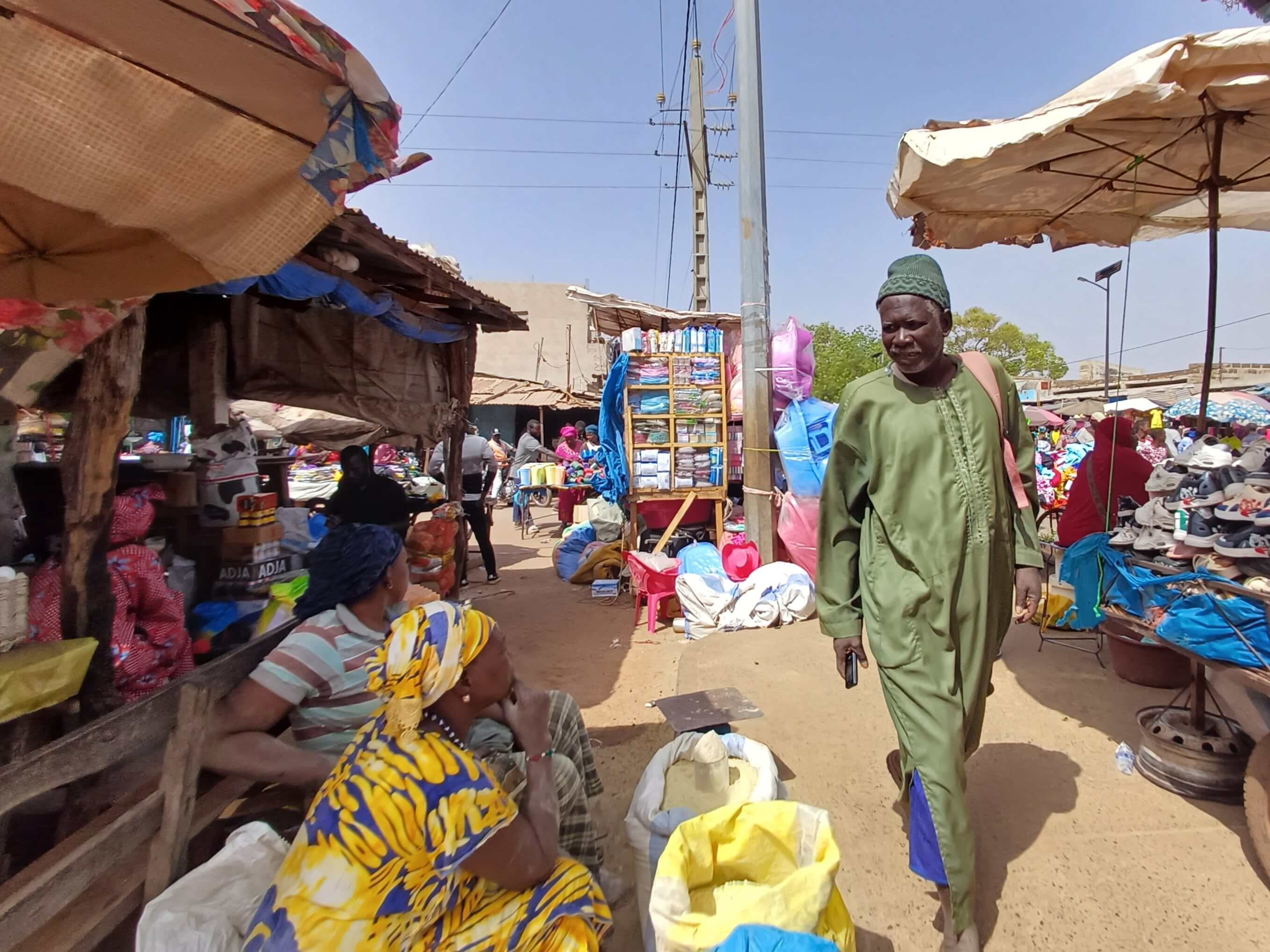 A man walking across a West African market, checking the stalls